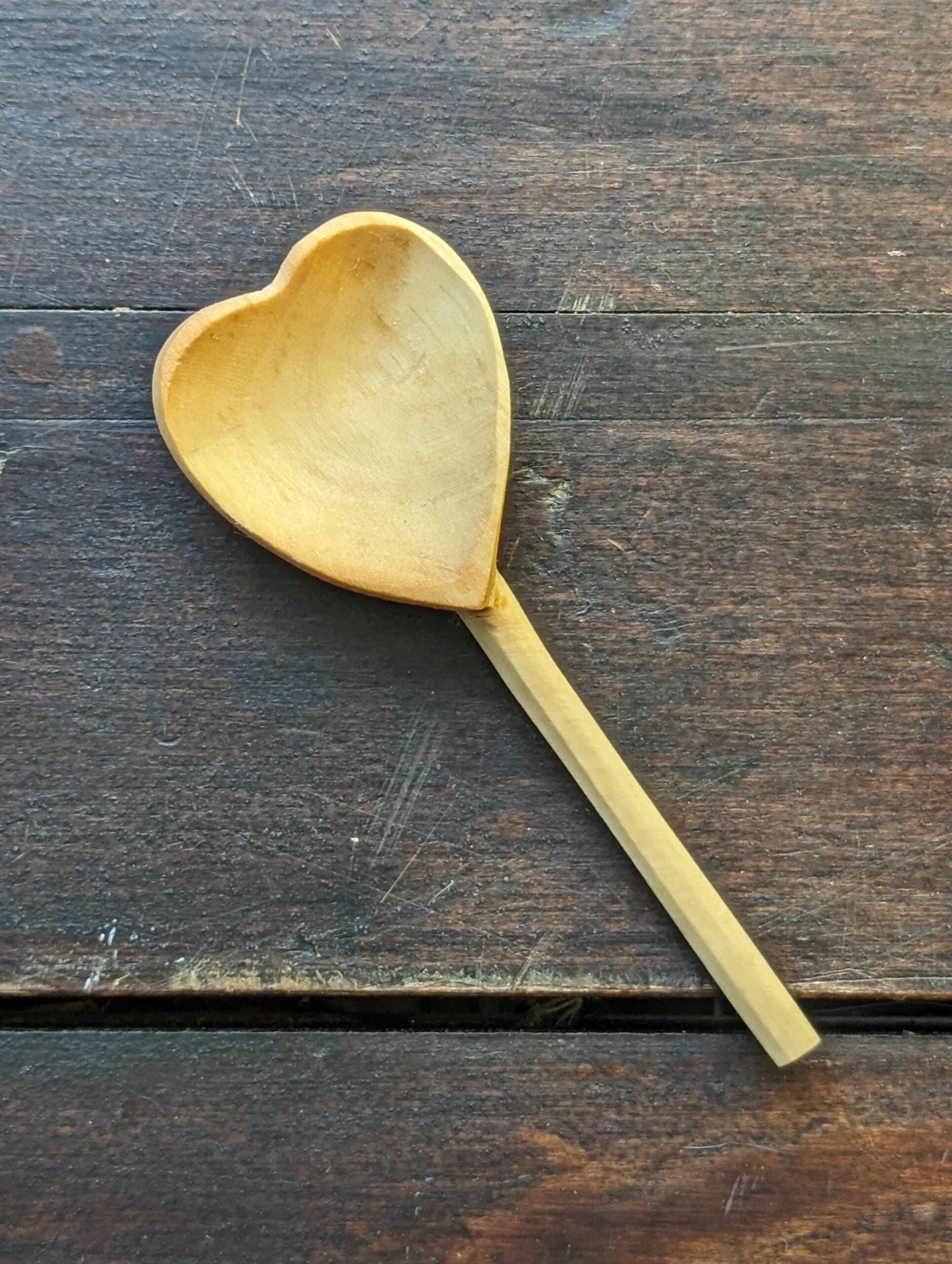 hand-carved wooden heart shaped teaspoon on a wood table